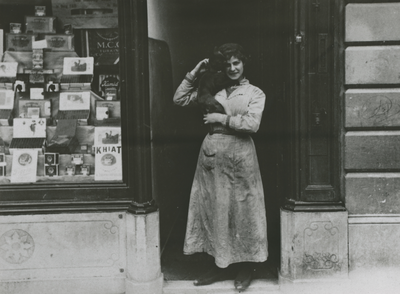 874829 Portret van het dienstmeisje Dien van den Oudenalder voor de ingang van de bovenwoning van de Koninklijke ...